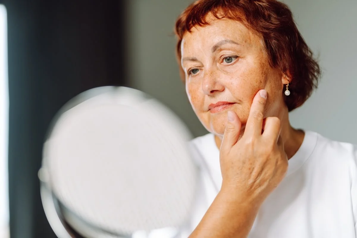 Žena s podezřením na obrnu lícního nervu zkoumá mimické svaly v zrcadle. Žena s podezřením na obrnu lícního nervu zkoumá mimické svaly v zrcadle.